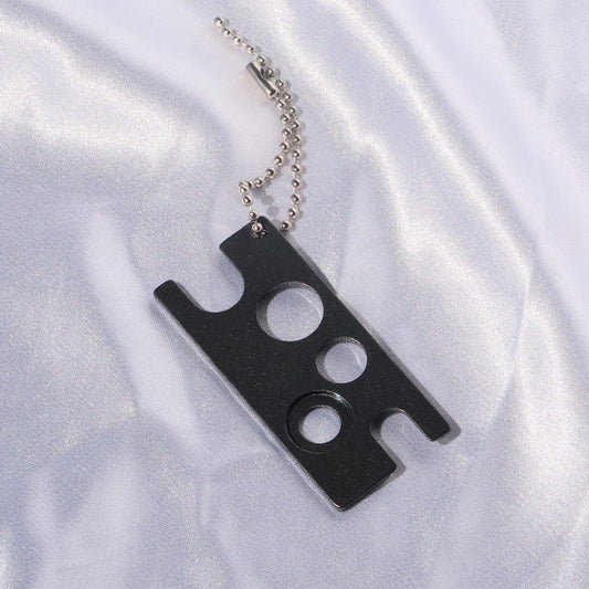 Black lash glue nozzle opener with multiple openings and a silver ball chain.