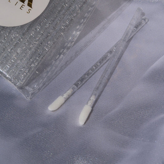 Close-up of disposable lip wands with white applicator tips and clear glitter handles.