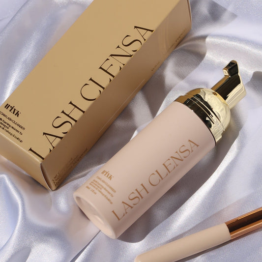 Close-up of Wink Supplies AU Lash Clensa foaming lash cleanser beside its gold box and cleansing brush.