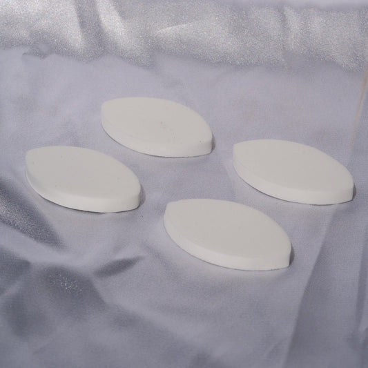 Close-up of four round white lash training practice sponges.