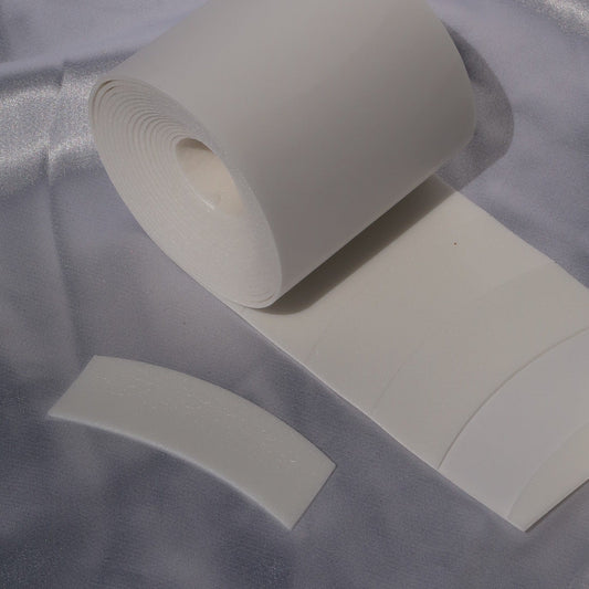 White precut foam lash eye pad roll with one curved pad displayed alongside.