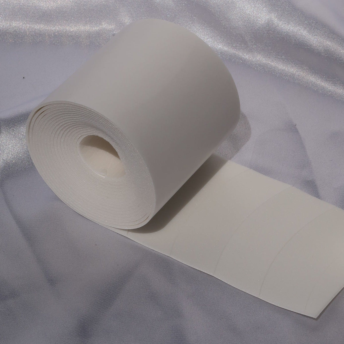 Roll of white precut foam under-eye pads for lash extension application.