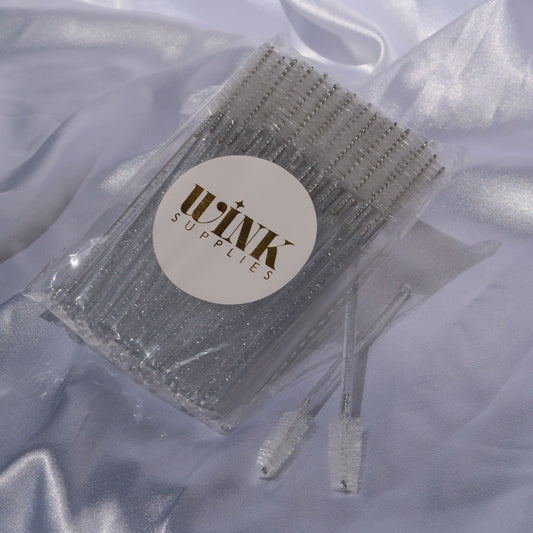 Pack of Wink Supplies AU lash spoolie brushes with white bristles and clear glitter handles.