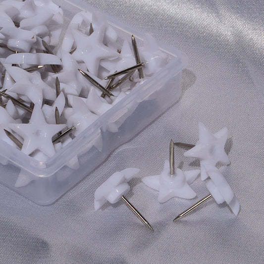Close-up of white star-shaped lash glue nozzle pins with metal tips in a clear storage box.